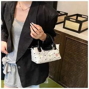 Dettaglio di una borsa bianca con ciondolo a forma di orso rosa e trama a pieghe
