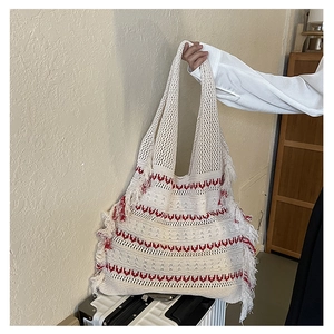 Detail view of beige knitted tote bag with red wave patterns and fringe accents