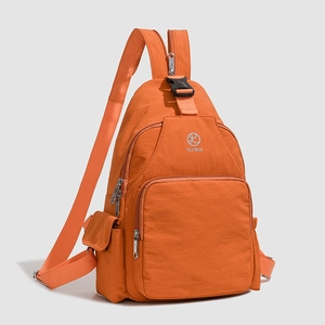 Detail view of the orange nylon multi-purpose backpack with brand logo and zipper compartments