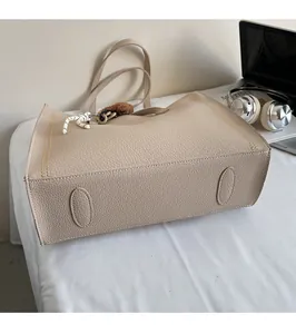 Detail of protective feet on bottom of large beige leather tote bag with stylish charms