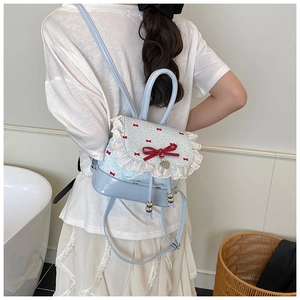 Close-up of light blue lace backpack with red bows and silver heart charm details