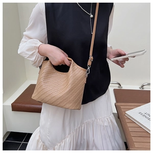 Detail of woven khaki bucket bag featuring herringbone pattern and detachable strap