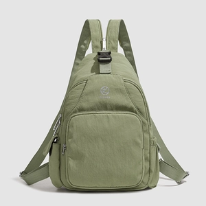 Detail view of sage green nylon backpack featuring multiple zippers and plastic buckle closure