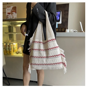 Detail of hand-woven cream tote bag with red wave patterns and long fringe accents