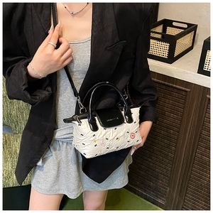 Dettaglio mini borsa bianca con ricami di fiocchi neri, cuori colorati e orsetti cartoon