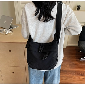 Detail of the black canvas crossbody bag with thick zipper and woven puller on shoulder