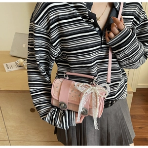 Pink cylindrical crossbody bag with rhinestones, lace bows and pearls in a study setting