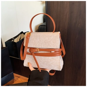 Détail du sac bandoulière en toile beige avec poignées en cuir marron et fermoirs dorés