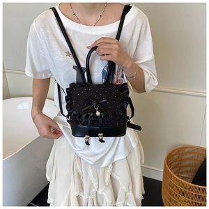 Detail of black lace backpack with pearl pendant, ruffle edges, and polka dot mesh