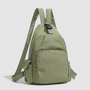 Close-up of light green nylon backpack showing front zipper pocket and KLEINAN logo