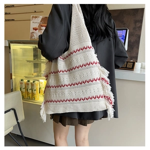 Macro detail of cream knit tote bag with red wave patterns and boho side tassels