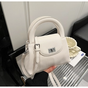 Detail of creamy white pleated handbag showing round handle and silver twist lock closure