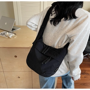 Detail shot of the minimalist black nylon crossbody bag with dual zipper pullers and logo