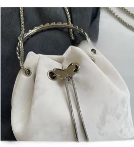 Close-up of white bucket bag featuring silver butterfly drawstring and matte leather texture