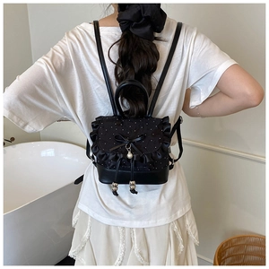 Detail of black mini backpack with lace ruffles, bow, and pearl charm decoration