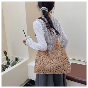 Detail of hand-woven straw tote bag with decorative dark brown wooden beads and rings