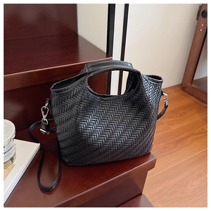 Close-up of black bucket bag showing the intricate hand-woven V-shaped leather texture