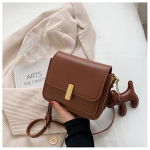 Brown faux leather crossbody square bag featuring a gold clasp and a cute dog charm accessory
