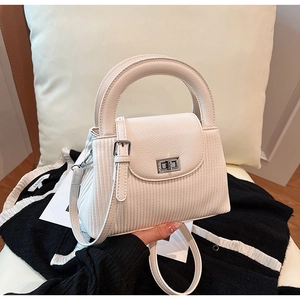 Detail view of cream bucket bag with striped leather texture and silver twist lock closure