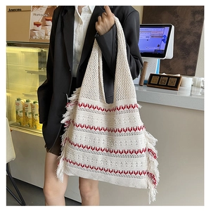 Detail of cream knit tote bag with red wave patterns and long side tassels in bohemian style