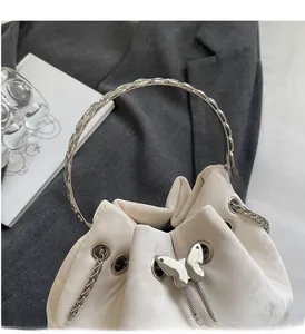 Detail of white leather bucket bag with silver butterfly charm and metal ring handle