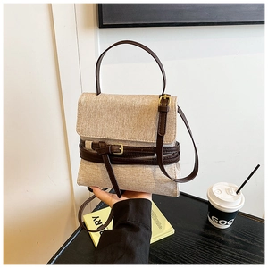 Détail du sac en toile beige avec lanières en cuir marron et boucles dorées