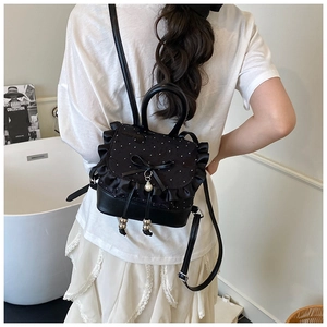 Detail of black leather backpack with lace trim, bow, and pearl charm decoration