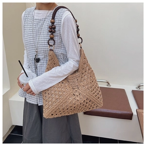 Detail of hand-woven straw tote with hollow crochet pattern and wooden bead shoulder strap