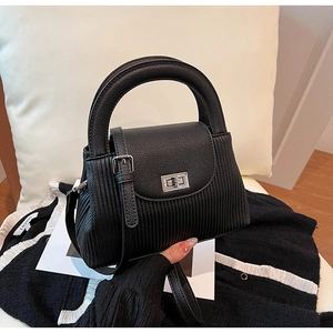 Detail of black pleated leather handbag featuring a silver rectangular twist lock closure