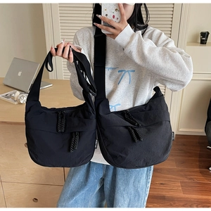 Detail view of large and small black nylon crossbody bags with woven zipper pulls
