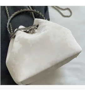 Detail of white velvet bucket bag with silver metal handle and chain strap