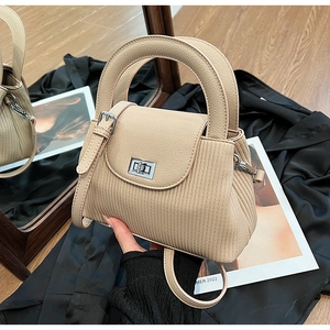 Detail of beige pleated bucket bag featuring metallic twist lock and smooth leather handle