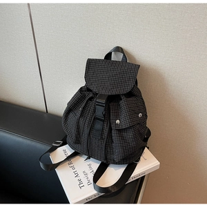 Detail eines schwarz-weiß karierten Rucksacks mit Schnallenverschluss und Seitentaschen