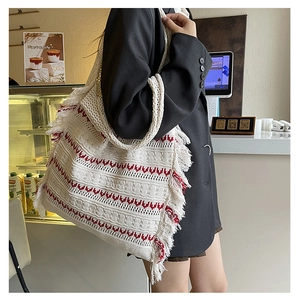 Close-up of knit tote bag featuring red wave patterns and stylish fringe edge details