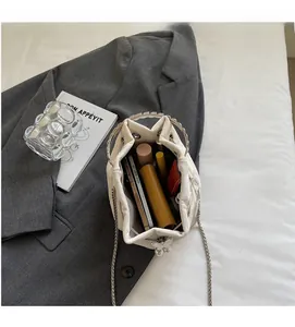 Internal capacity of white bucket bag showing storage for phone and cosmetics