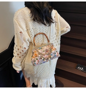 Detail of cute bear shell bag with bamboo handle and pearl chain on vintage stairs