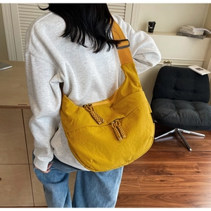 Detail of yellow nylon dumpling bag with adjustable shoulder strap and woven zipper pull