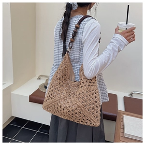 Detail of woven straw tote bag featuring bohemian geometric patterns and wooden bead strap