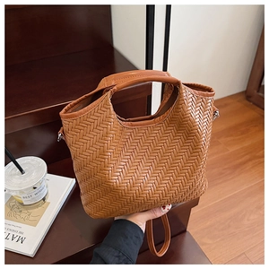Detail of a brown woven leather bucket bag with an intricate Intrecciato style craftsmanship