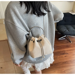 Detail view of cream drawstring bucket bag with pearl pendant and round metal handle