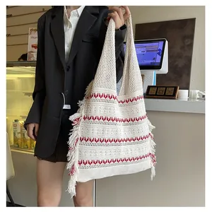 Detail of hand-woven crochet tote bag featuring red wavy patterns and long fringe tassels