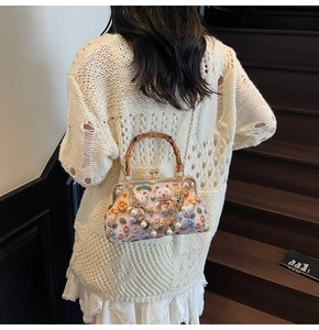 Detail of pink embroidered crossbody bag with bamboo handle and gold chain strap