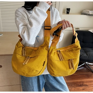 Detail of ginger yellow nylon crescent bags with woven zipper pulls and wide straps