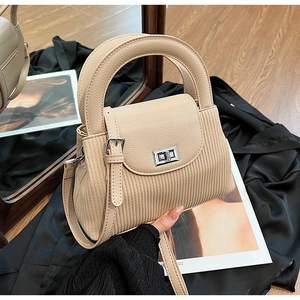 Detail view of beige pleated leather handbag with silver twist lock and round handle