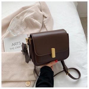 Detail of vintage brown leather crossbody bag with gold buckle and bear charm accent