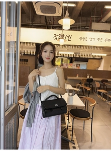 Classic black leather crossbody bag with silver metal lock shown on a model's arm
