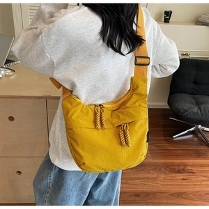 Detail view of ginger yellow crescent crossbody bag with adjustable wide strap on model