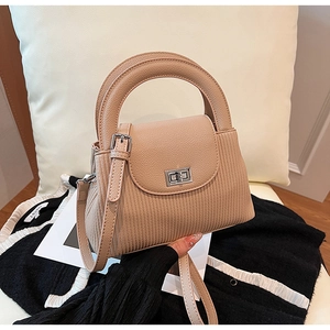 Detail of apricot corduroy handbag featuring round handles and a silver metal turn-lock