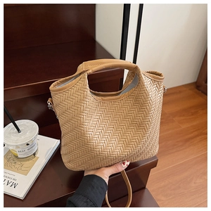 Detail of tan woven leather tote bag with top handle and strap in an elegant setting