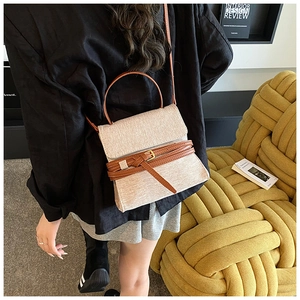 Détail d'un sac bandoulière en toile avec bordure en cuir marron porté par un mannequin